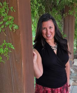 Rhonda Banuelos, Author, standing next to a post on a patio