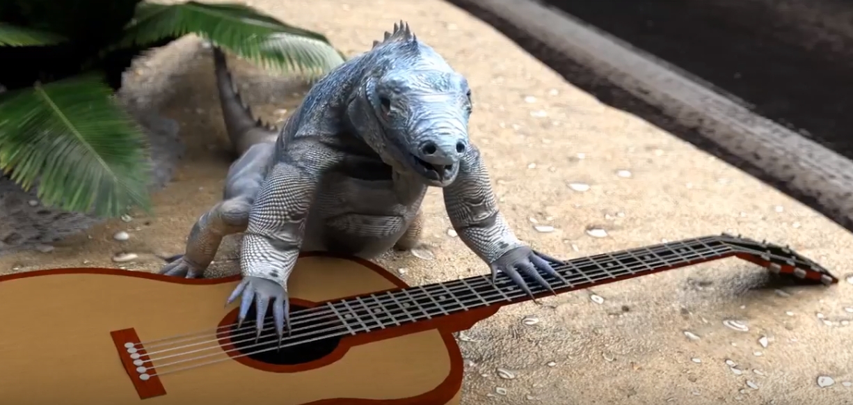 A rock iguana with a guitar, singing, on a sidewalk, near the road