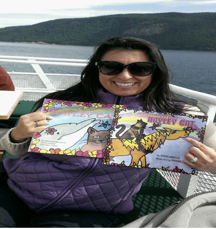 A woman on a boat, holding up a children's book