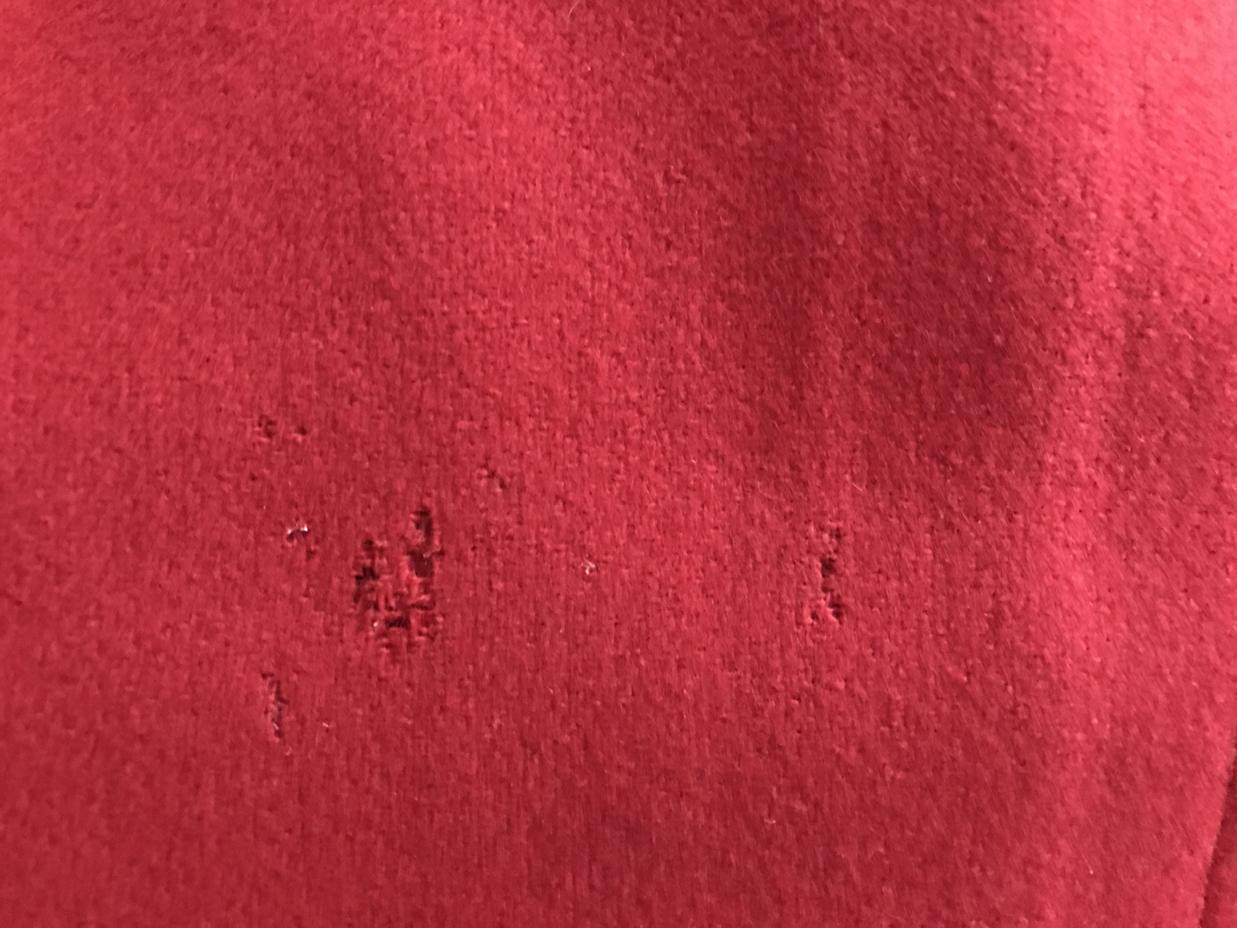 a patch of a red woolen coat showing a hole