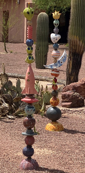An outdoor sculpture of stacked planets, rocket ships, and green alien heads.