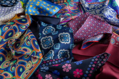 A colorful array of untied bowties laid out on a surface.