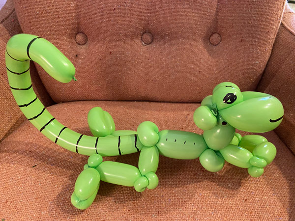 A green balloon shaped into a curly tail lizard.