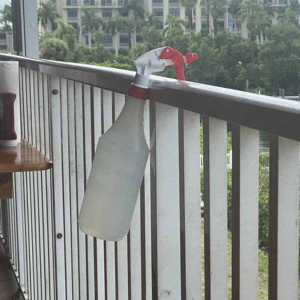 A spray-bottle hangs from the railing where grackles perch nearby.
