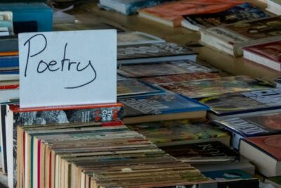 Rows of books on a bookseller table, a sign labeled "poetry" sits prominently.