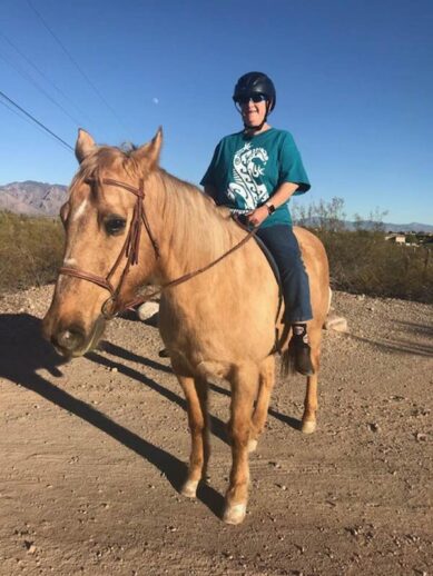 Elaine, sitting atop Lady, a light brown horse.