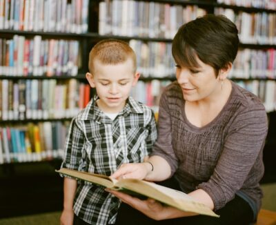 A parent and child reading a book in a library.