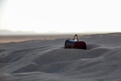 A treasure chest half-buried in the sand of a desert.