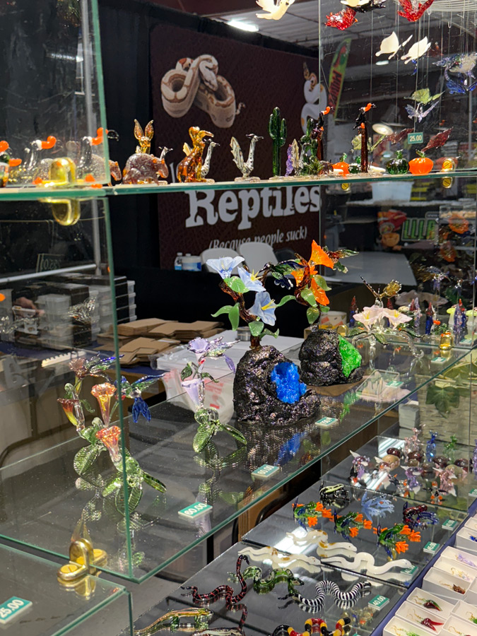 Intricate blown class sculptures of various reptiles on a glass display shelf.