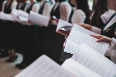 choristers in white and green uniform performing on stage.