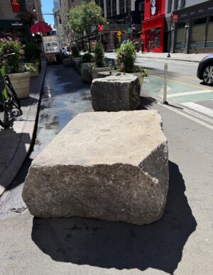 A large flat rock positioned on a side walk.